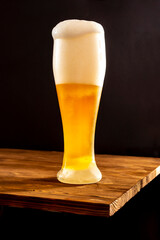 Light craft beer in a misted glass on a wooden table.