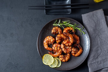 Grilled fried shrimp on a black plate dark background top view