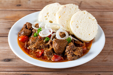 Czech traditional goulash with breaded dumpling and onion on white plate on table - obrazy, fototapety, plakaty