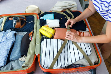 Young woman packing suitcase for travel