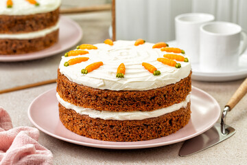Kitchen table with homemade carrot cake made with walnuts, iced with cream cheese. Sweet dessert. White marble background.