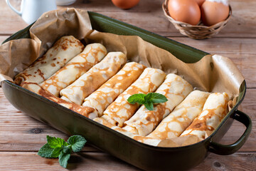 Thin pancakes with cottage cheese and raisins on wooden table. Healthy traditional breakfast concept.