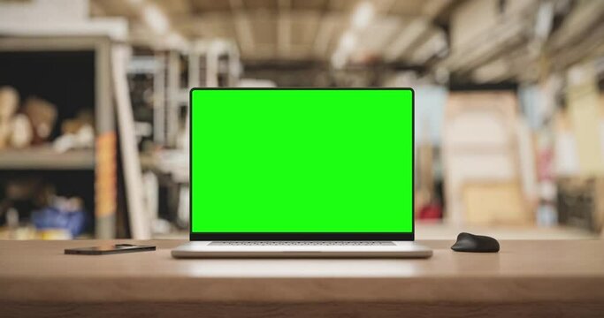 Laptop with a blank screen on the table with a mouse and smartphone smooth camera zoom in. Factory background, 4k 30fps. 3d render