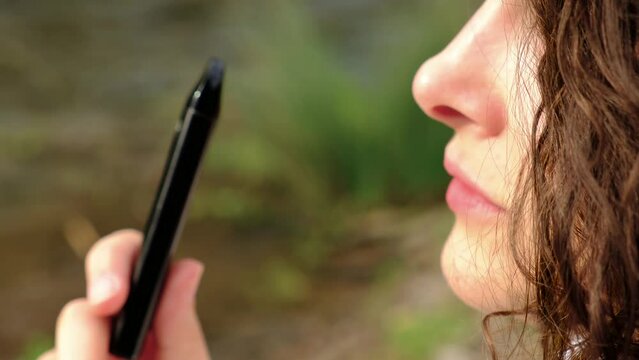 Portrait of a woman smoking electronic cigarette in a park. Closeup thoughtful girl with e-cigarette in hand.