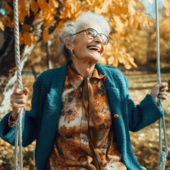 A happy elderly woman laughs on a swing in the autumn garden