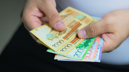 Hands holding Kazakh tenge banknotes