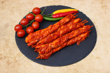 Grillfackeln. Auf Spieße gewickelte Schweinebauchscheiben  auf einer Schieferplatte mit Tomaten und Pepperoni.