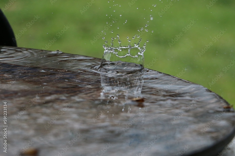 Wall mural rain is falling on a wooden table full of water in the garden