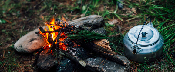 Camping kettle near small camp fire close-up. Cozy camping place in wild. Wonderful evening atmospheric background of campfire. Beautiful flame of small magic bonfire. Romantic warm place with fire.
