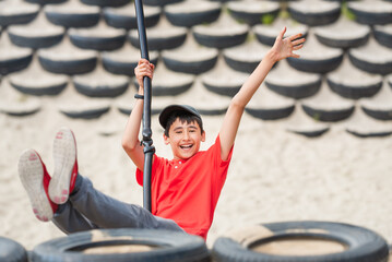 Happy teenage boy is flying on hanging swing in an amusement park.