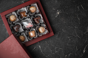 Set of homemade chocolate bonbons in an open gift box. Assortment of hand painted chocolate candy with marble coating. Mockup with a copy space for a free text for chocolatier products.