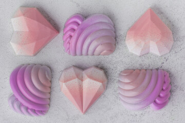 Set of homemade pink heart-shaped chocolate bonbons. Assortment of hand painted candies. Copy space. Macro shot of  chocolatier products on white marble background. Top view. Happy Valentine's Day