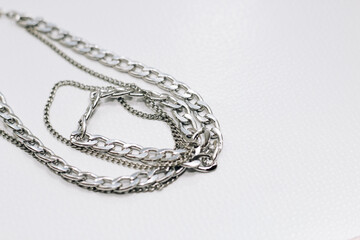 Different silver metal chains on a light background.