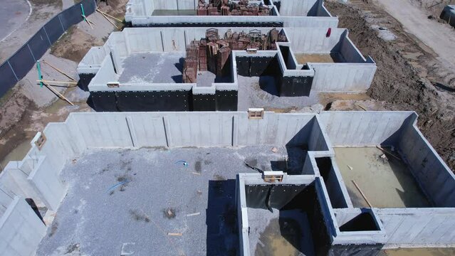 Cement foundation base work of townhouse construction. Concrete basement walls made of poured liquid concrete or cement reinforcement. City housing building foundation construction.