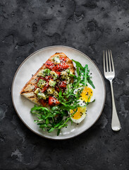 Healthy breakfast, snack - avocado, tomatoes bruschetta, boiled egg and arugula on a dark background, top view