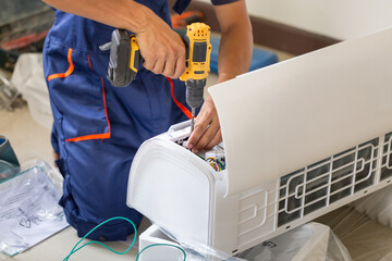 Asian technician man installing an air conditioning in a client house, Young repairman fixing air...