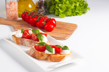 Tomato, basil and cheese fresh made caprese bruschetta. Italian tapas, antipasti with vegetables, herbs and oil on grilled ciabatta and baguette bread. Sandwich.