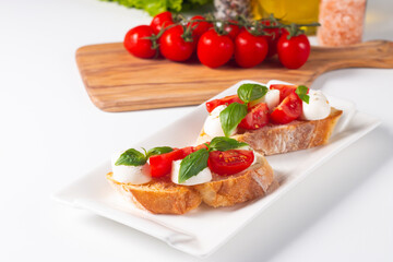 Tomato, basil and cheese fresh made caprese bruschetta. Italian tapas, antipasti with vegetables, herbs and oil on grilled ciabatta and baguette bread. Sandwich.