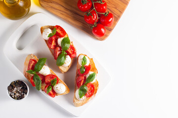 Tomato, basil and cheese fresh made caprese bruschetta. Italian tapas, antipasti with vegetables, herbs and oil on grilled ciabatta and baguette bread. Sandwich.