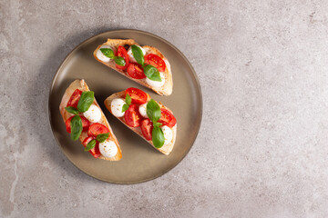 Tomato, basil and cheese fresh made caprese bruschetta. Italian tapas, antipasti with vegetables, herbs and oil on grilled ciabatta and baguette bread. Sandwich.