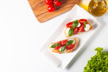 Tomato, basil and cheese fresh made caprese bruschetta. Italian tapas, antipasti with vegetables, herbs and oil on grilled ciabatta and baguette bread. Sandwich.