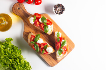 Tomato, basil and cheese fresh made caprese bruschetta. Italian tapas, antipasti with vegetables, herbs and oil on grilled ciabatta and baguette bread. Sandwich.