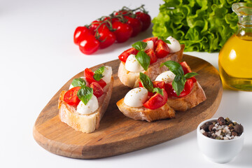 Tomato, basil and cheese fresh made caprese bruschetta. Italian tapas, antipasti with vegetables, herbs and oil on grilled ciabatta and baguette bread. Sandwich.