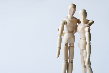 Two unrecognizable anthropomorphic mannequins of different heights hug each other. The concept of love, sympathy, friendship and patronage. Copy space. Light background.