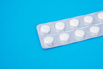 Pills in blister on blue background with space for text