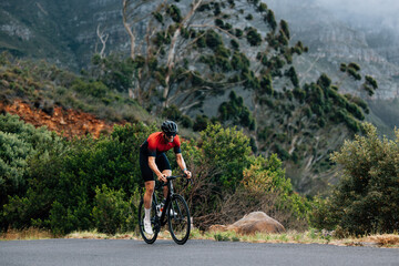Fototapeta premium Young male doing intense training on bicycle in wild terrain. Man doing a training on bicycle.