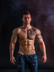 Confident, attractive shirtless muscular man on black background
