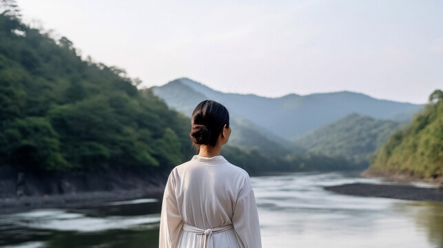A person practicing mindfulness overlooking a valley river with their back to the camera