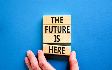 The future is here symbol. Concept words The future is here on wooden block. Beautiful blue table blue background. Businessman hand. Motivational business the future is here concept. Copy space.