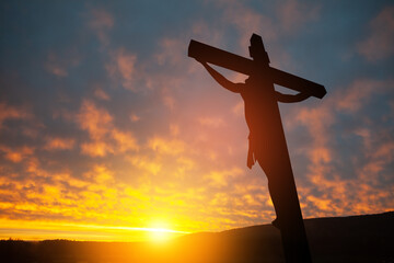 Silhouette of the crucified Jesus Christ on the cross on background of sunset.
