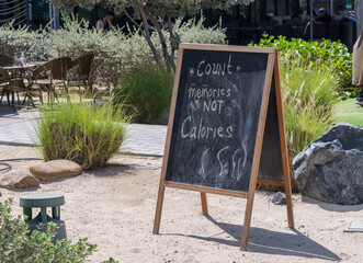 Wooden blackboard with Count Memories not Calories outside cafe in beach town