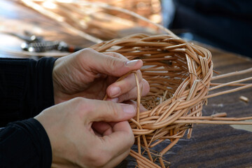 Hands of a folk craftsman weaving a traditional wicker basket in close-up
