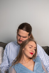 Happy man in striped shirt hugs beautiful loving woman with long hair, red lips, light blue dress. A couple enjoying a romantic time together.