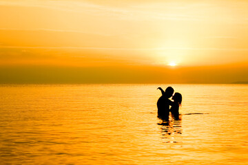 Naklejka na ściany i meble A happy couple in the sea on nature travel silhouette