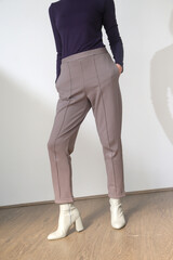 Female model wearing grey smart casual high rise trousers. Studio shot.	