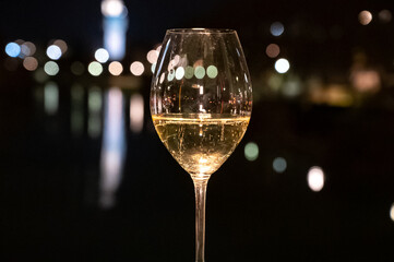 Tasting of french sparkling white wine with bubbles champagne outdoor at night with view on Marne river and lights of Epernay city in winter