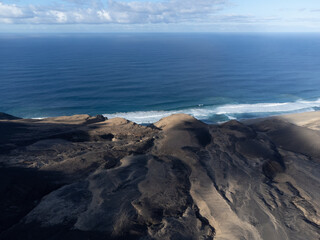 View on difficult to access golden sandy Cofete beach hidden behind mountain range on Fuerteventura, Canary islands, Spain