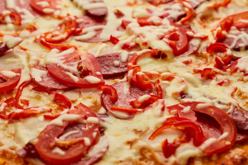 Freshly baked pizza with smoked sausages, red pepper and tomatoes served on wooden background with sauce and herbs. Food delivery concept. Restaurant menu