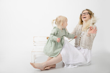 Portrait of pretty little girl holding branch of dried pampas grass, tickling young laughing woman...