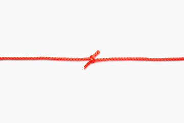 The two ends of a red rope are tied into a knot on a white isolated background. Red nylon rope with...