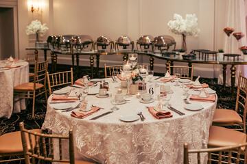 The reserved round table in the restaurant is decorated with flowers and candles. A round table for guests in the restaurant is set for a large company. Table number six