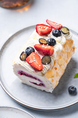 Meringue roll with almond petals, cream, jam and fresh berries close up. Delicious homemade healthy pastries. Celebration  food.