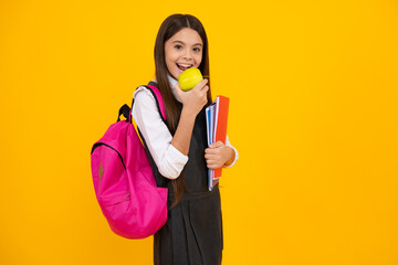 Schoolchild, teenage student girl with school bag backpack hold aplle and books on yellow isolated studio background. Children school and education concept.