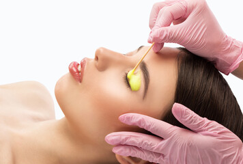 Make-up artist makes the procedure of lamination and dyeing of eyelashes to a beautiful woman in a...