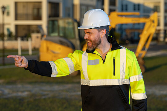 Worker at construction site. Builder in hardhat. Construction man with helmet. Worker at construction with helmet. Industry worker at construction building. Builder at site building with excavator.