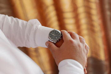 Man businessman checks the time on his wrist watch
